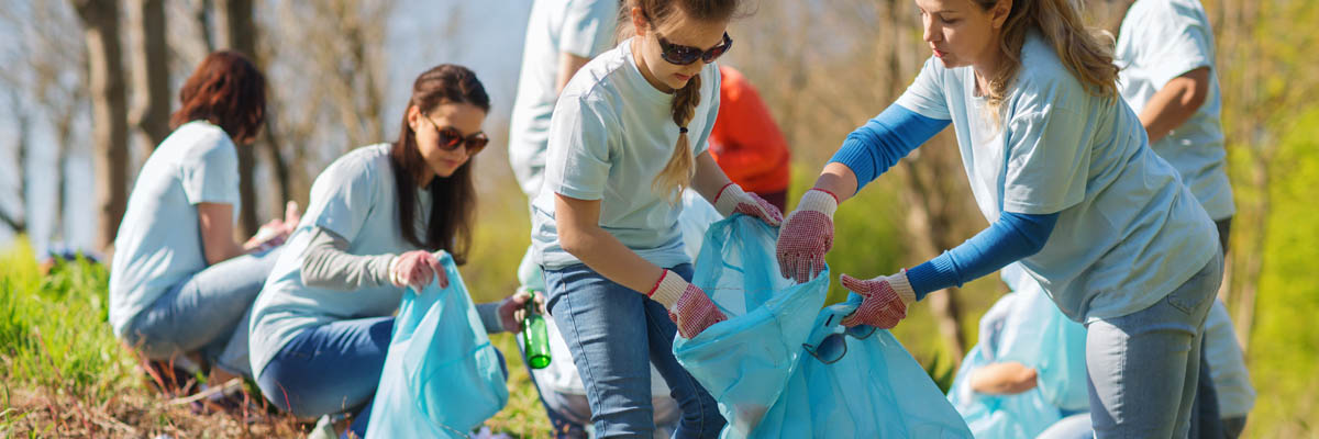 A group of volunteers outside putting trashing into a bag.